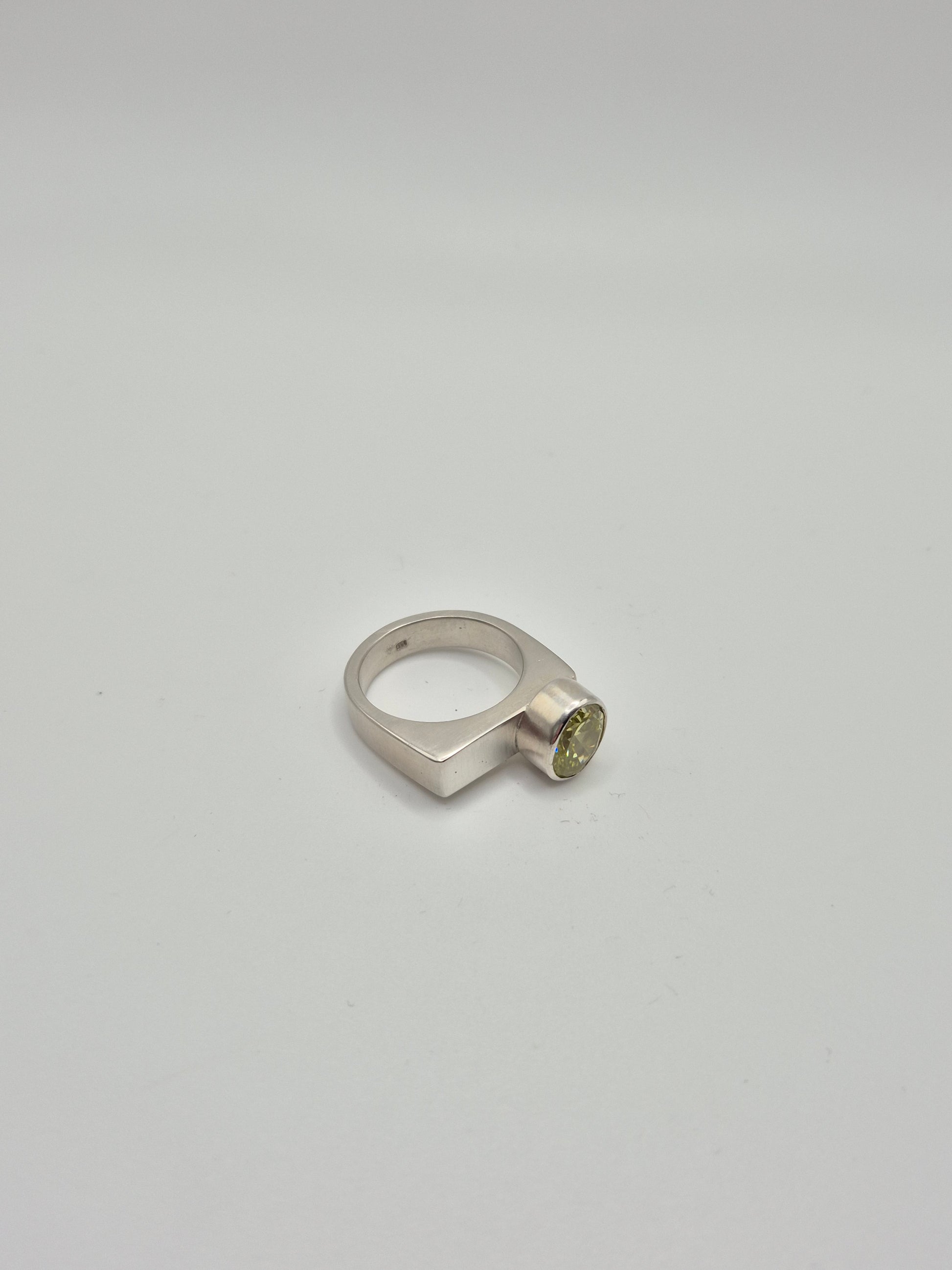 Close-up of acid green cubic zirconia stone in sterling silver ring setting