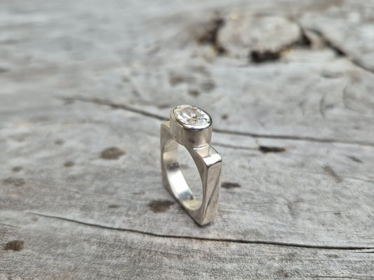 A Sterling Silver and Cubic Zirconia Ring with a modern square band and a centrally placed cubic zirconia stone on a wooden surface.
