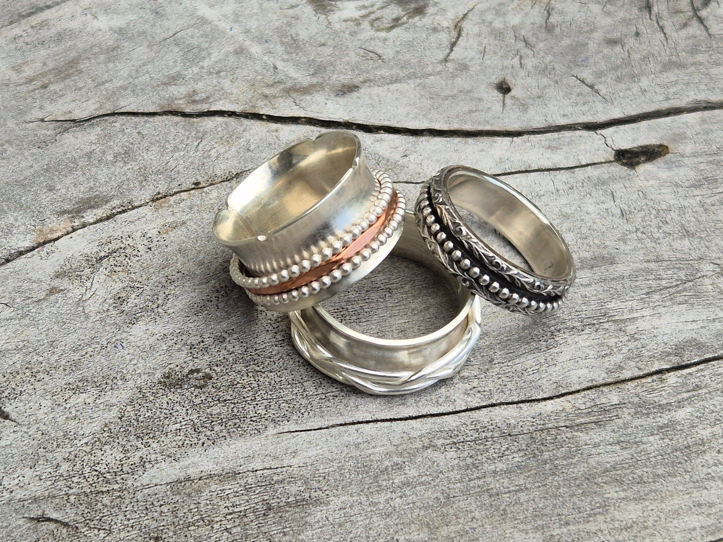 Photo of three sterling silver spinner rings on wooden surface