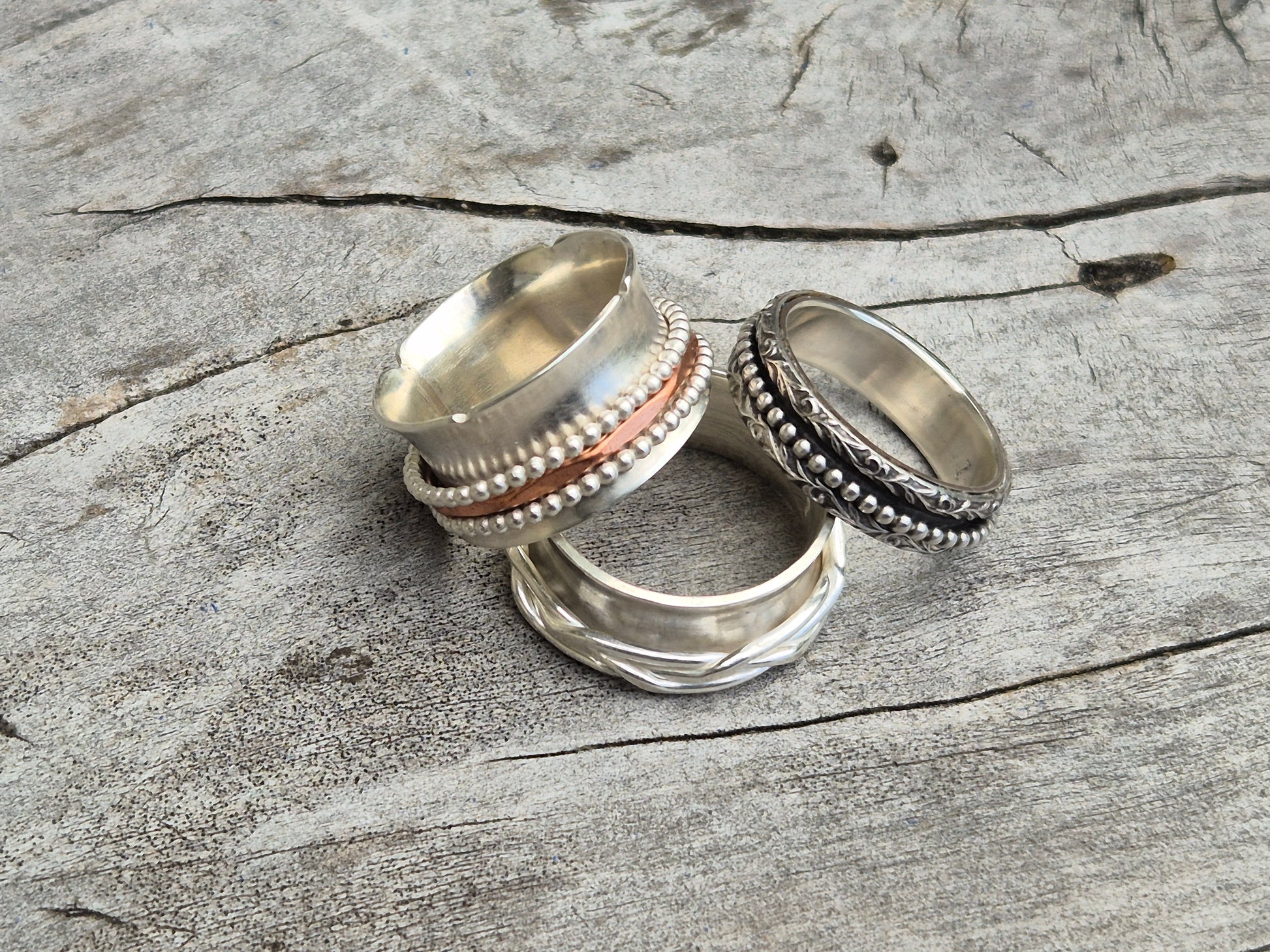 Photo of three sterling silver spinner rings on wooden surface
