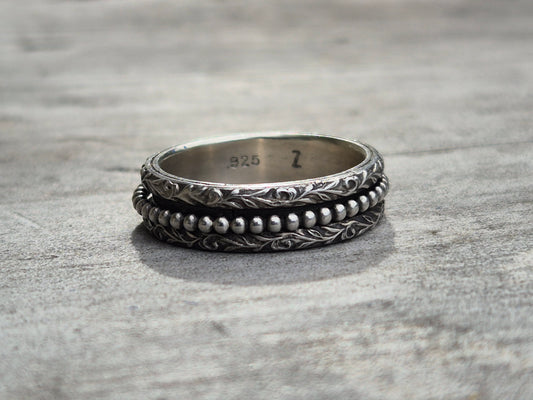 A handmade sterling silver spinner ring with two detailed bands and beaded inner band. The ring has been blackened