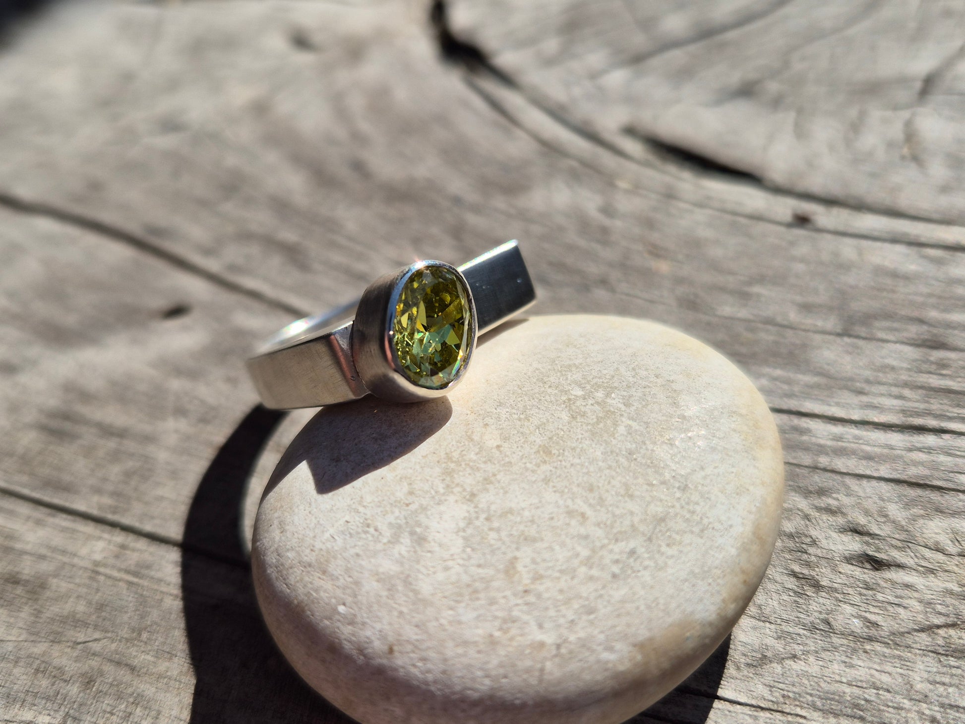 Sterling silver and acid green cubic zirconia ring side view on wood background