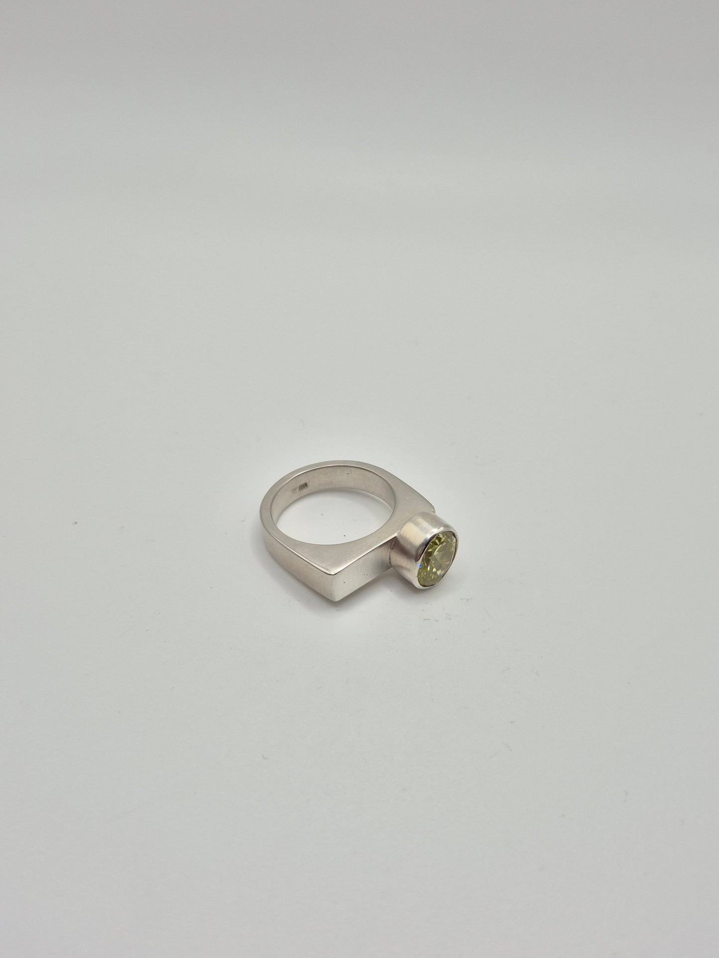 Close-up of acid green cubic zirconia stone in sterling silver ring setting