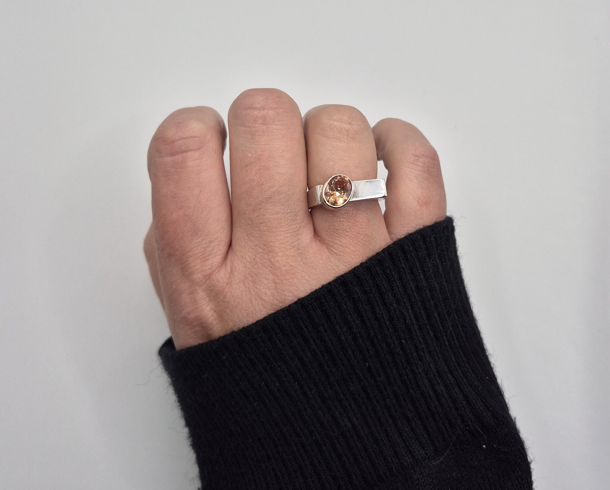 Sterling silver and champagne cubic zirconia ring worn on hand with black jumper sleeve