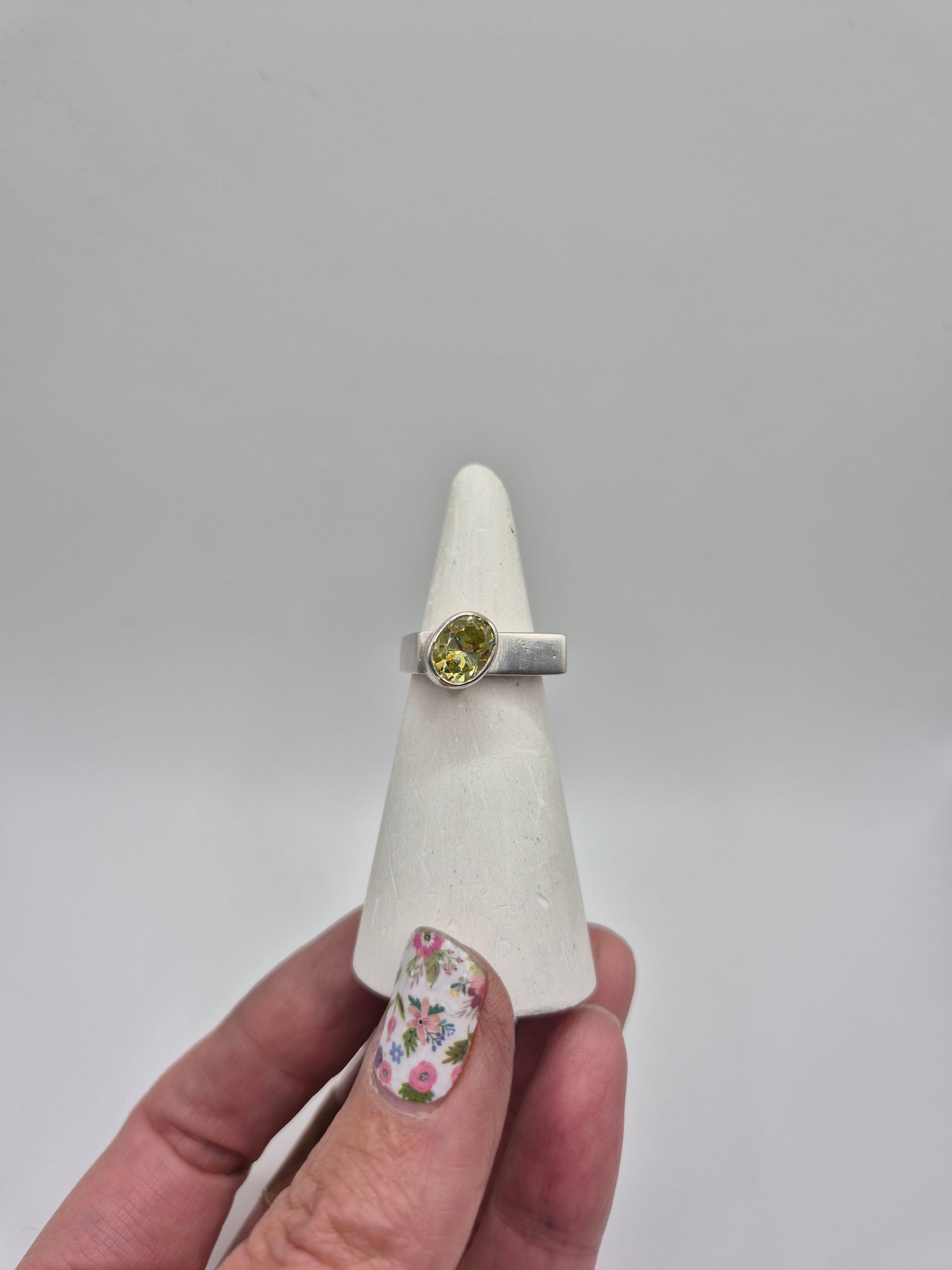 Acid green CZ ring on white ring cone showing bright lime green gemstone in silver setting