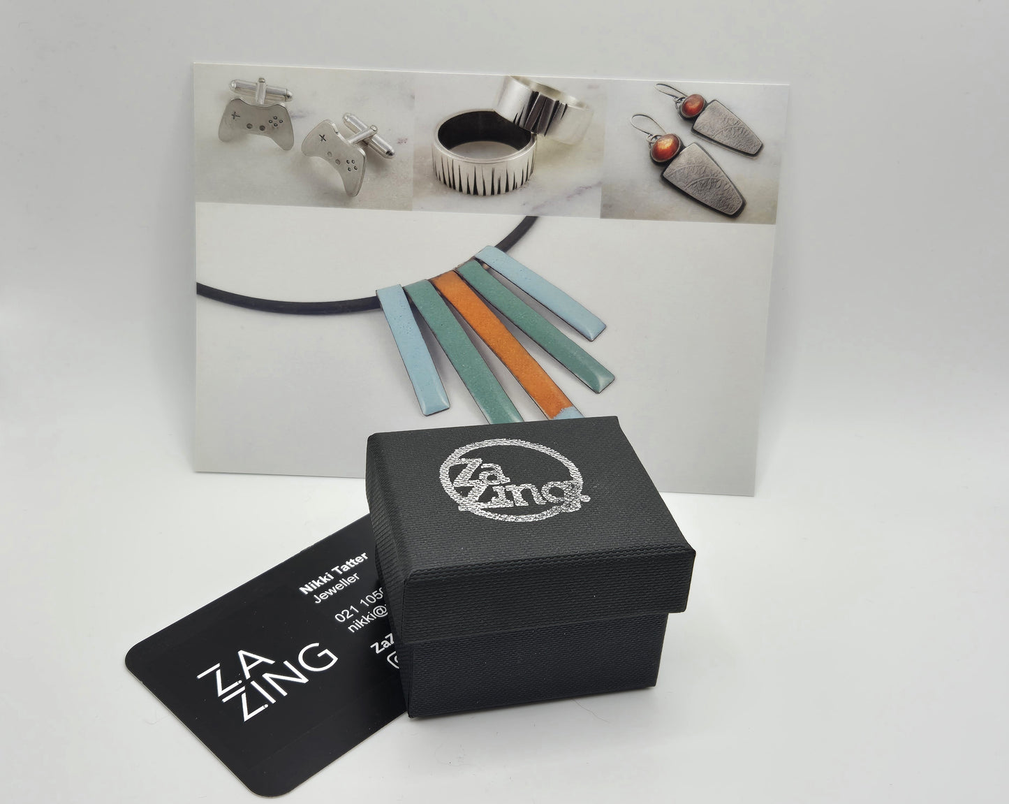 Black ring box with silver zazing logo and business card.  A thank you card is in the background