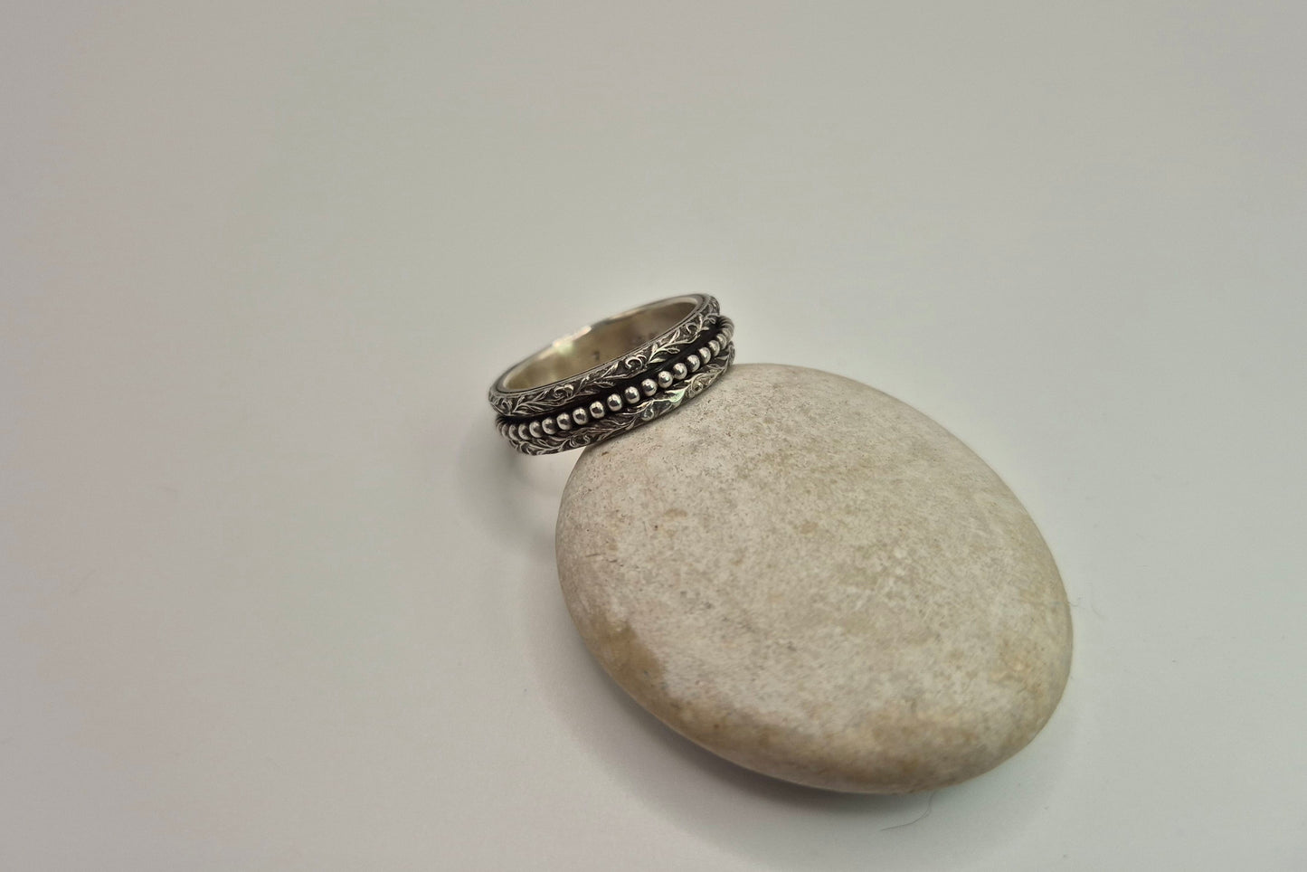 Detailed spinner ring on pebble to show ring face